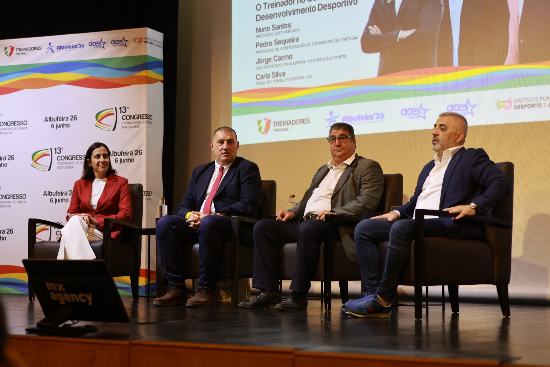 Painel de conferência com quatro pessoas sentadas, fundo com logotipos e texto do congresso desportivo.